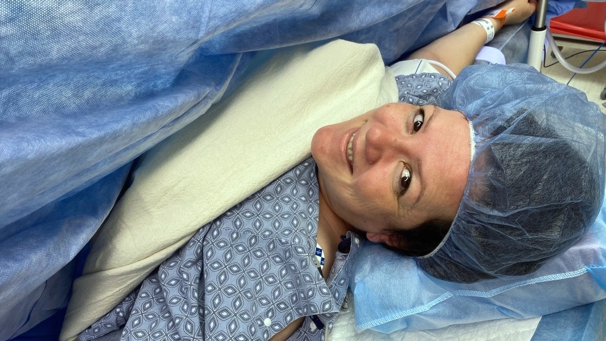 Annie smiling on the operating table in a blue surgical cap, moments before her C-section